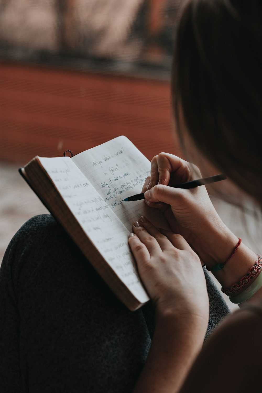 Mão escrevendo em caderno — devocional e microdesafio do dia